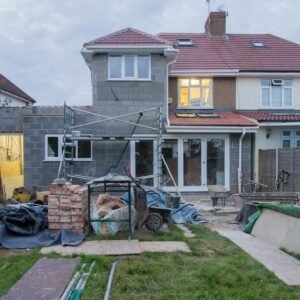 A suburban house undergoing major renovations with scaffolding and building materials.